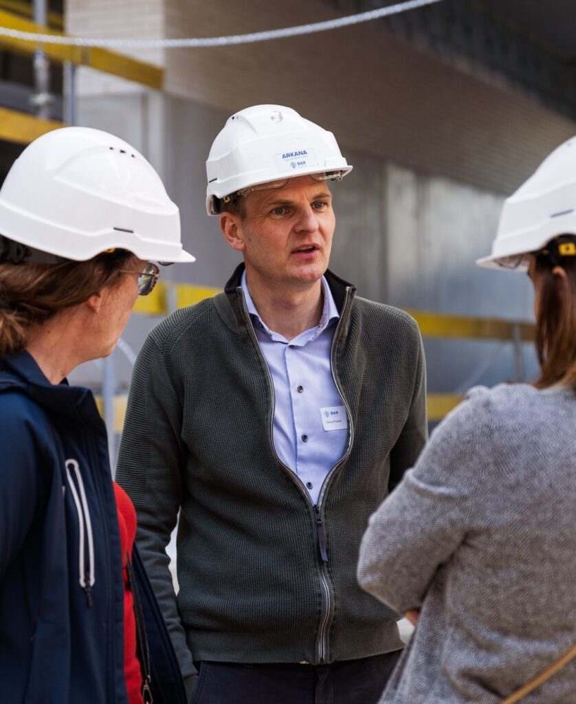 Twee personen met harde hoeden in gesprek op de werf