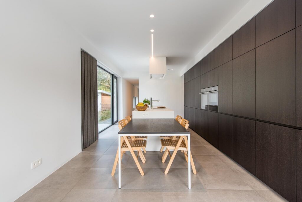 Eetkamer met eettafel en donkere keuken &mdash; woning Lambaert, Zoersel