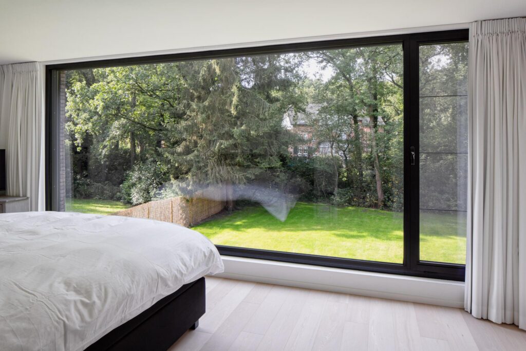 Leefruimte met grote ramen en tuinzicht &mdash; woning De Clercq, Brasschaat