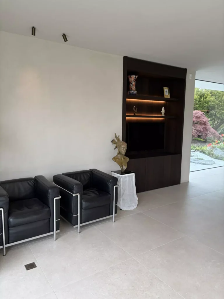 Leefruimte met donkere sofa en boekenplank &mdash; woning Boons, Wuustwezel